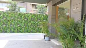 A building entrance with a green vertical garden, potted plants, and a sign indicating 'RIGHTS OF ADMISSION RESERVED'.