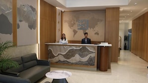 A hotel reception area with a modern design, featuring a reception desk, a sofa, and a coffee table.