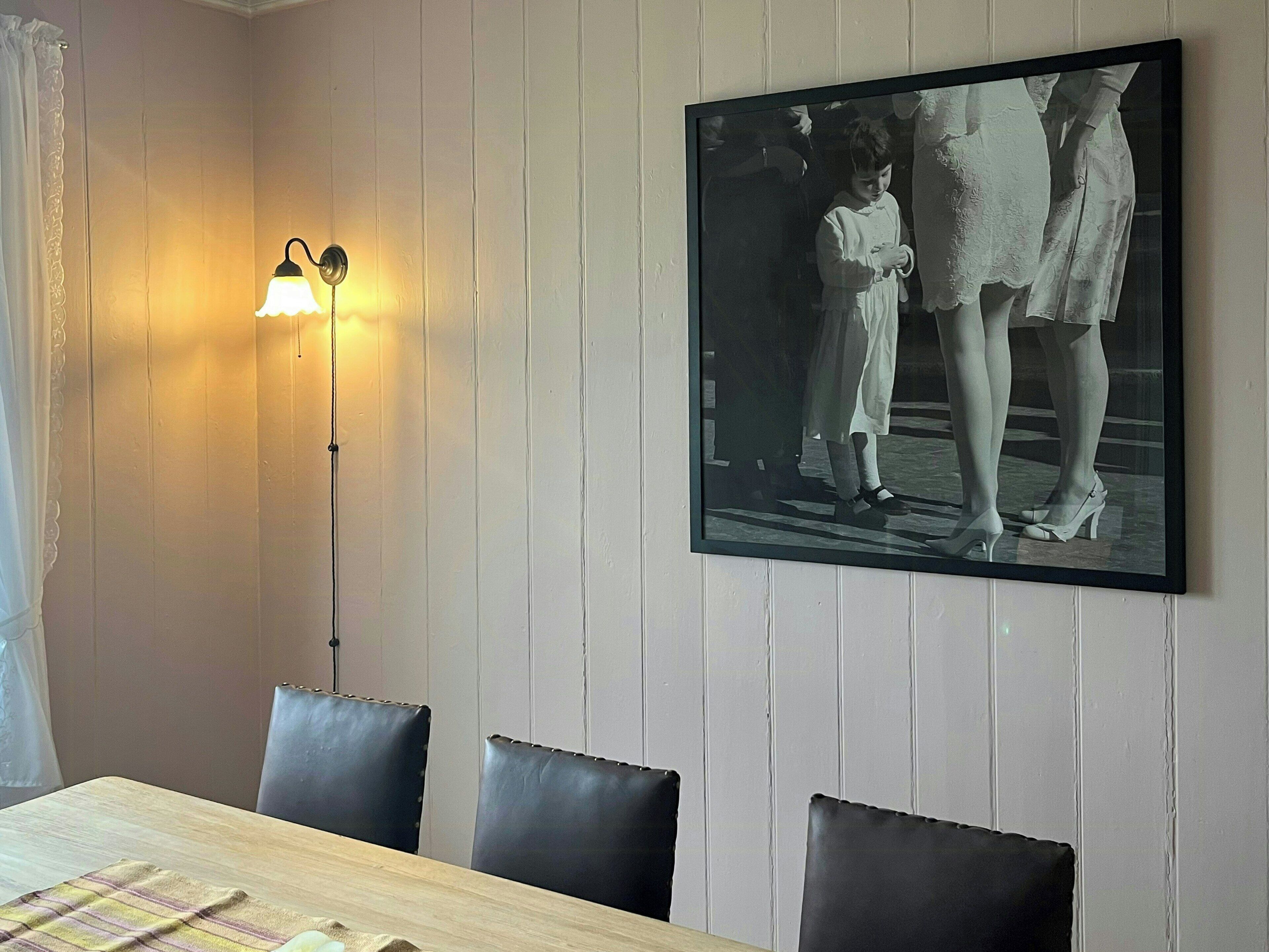 Ein Essbereich mit einem Holztisch, schwarzen Stühlen, einem Wandbild und einer Stehlampe.