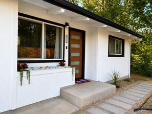 A modern house with a white exterior, a wooden door, and a window with a curtain. - Creekside Retreat House in Eagle Point (Eagle Point)