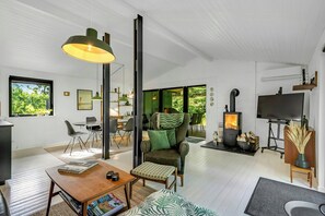 Un salon moderne avec une cheminée, un téléviseur et un coin repas comprenant des chaises et une table.