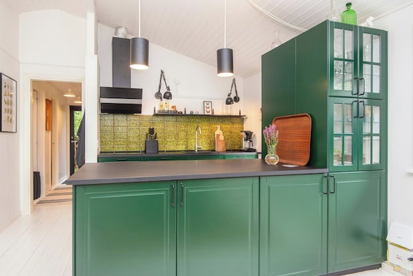 A kitchen with green cabinets, a black countertop, and pendant lights. - Summer house in Houstrup with scenic views (Nørre Nebel)