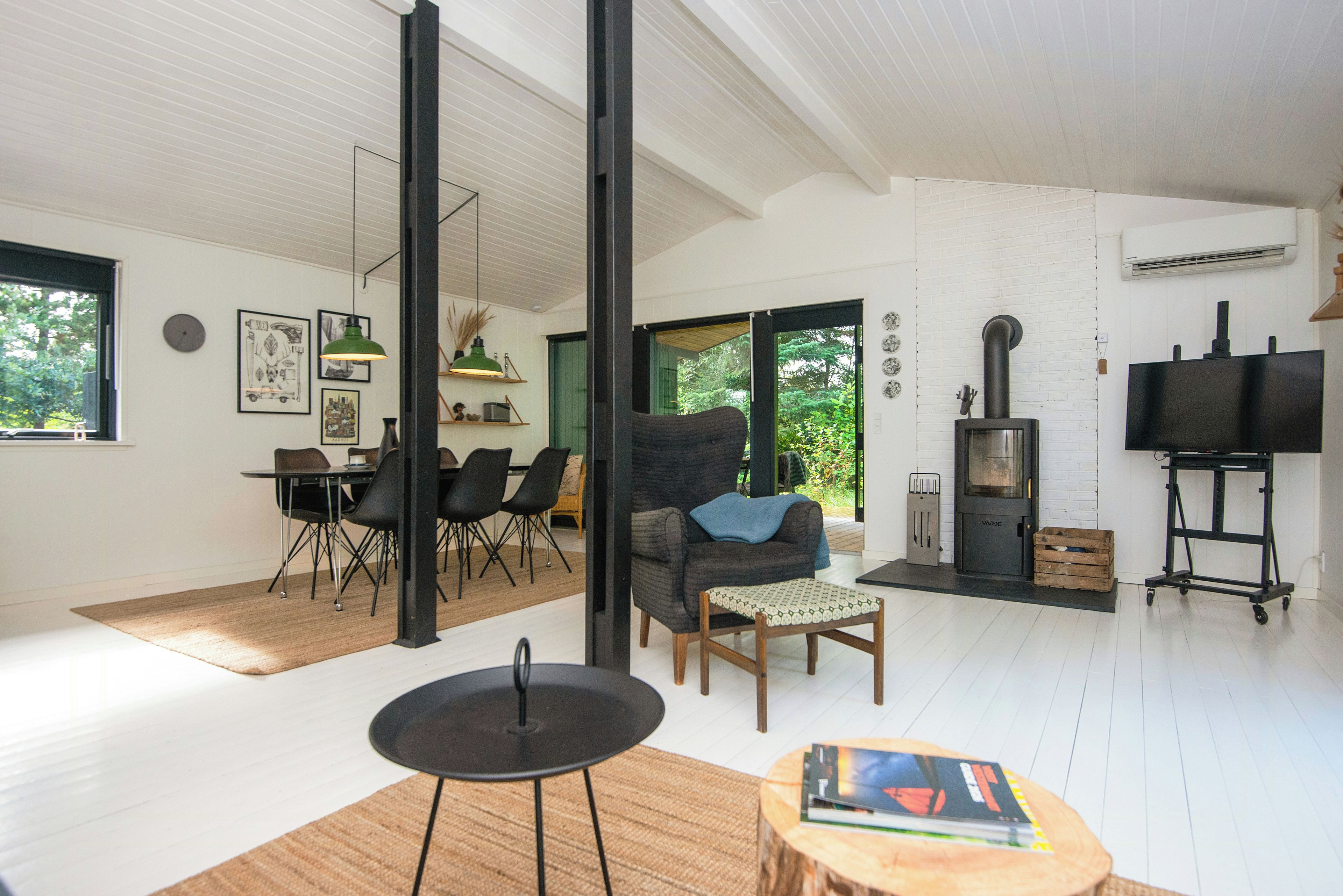 A modern living room with a dining area, a fireplace, and a television.