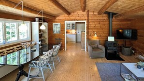 A cozy cabin interior with a dining area, kitchen, and living space. - Log cabin on beautiful natural grounds in Hornbæk (Hornbæk)