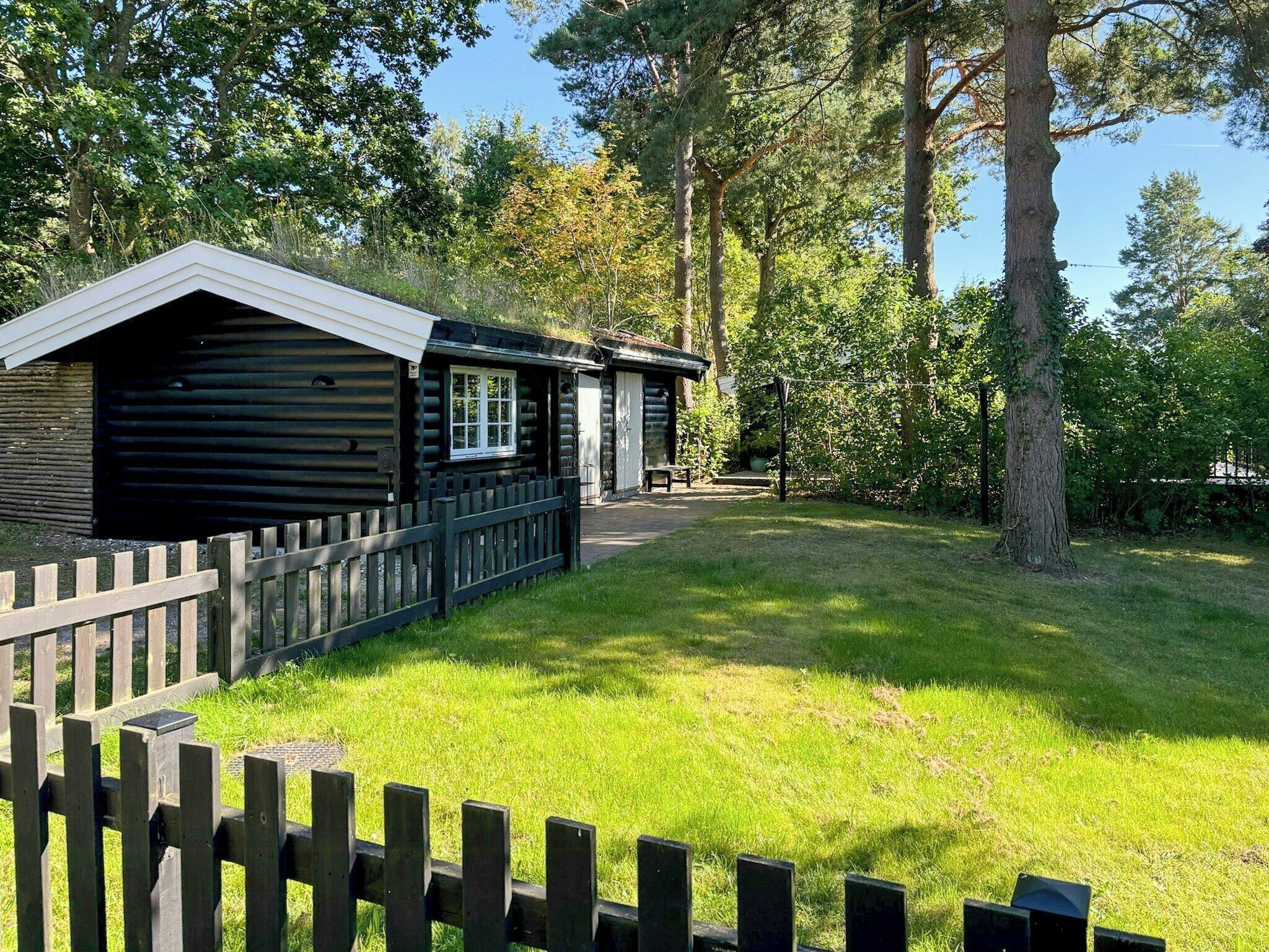 A log cabin with a fenced yard and a bench.