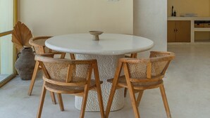 Ein runder Esstisch mit vier Holzstühlen, einer Vase und einer Wandleuchte.