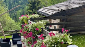 A stone staircase leading to a wooden deck with outdoor seating and flower planters. - Restored 19th century house with Dolomites view (Sauris di Sopra)