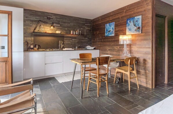 A modern kitchen with a wooden wall, a dining table with chairs, and a coffee machine. - Restored 19th century house with Dolomites view (Sauris di Sopra)