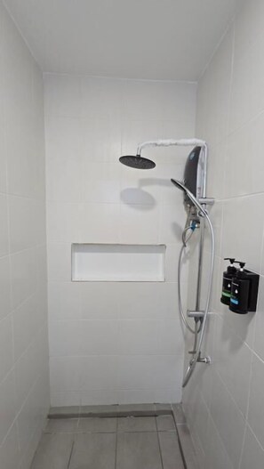 A small, enclosed shower area with a handheld showerhead and a wall-mounted faucet. - One Point Hotel TT3 Tabuan Tranquility (Kuching)
