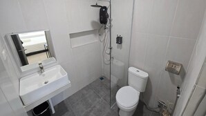 Un baño con lavamanos blanco, inodoro y cabina de ducha.