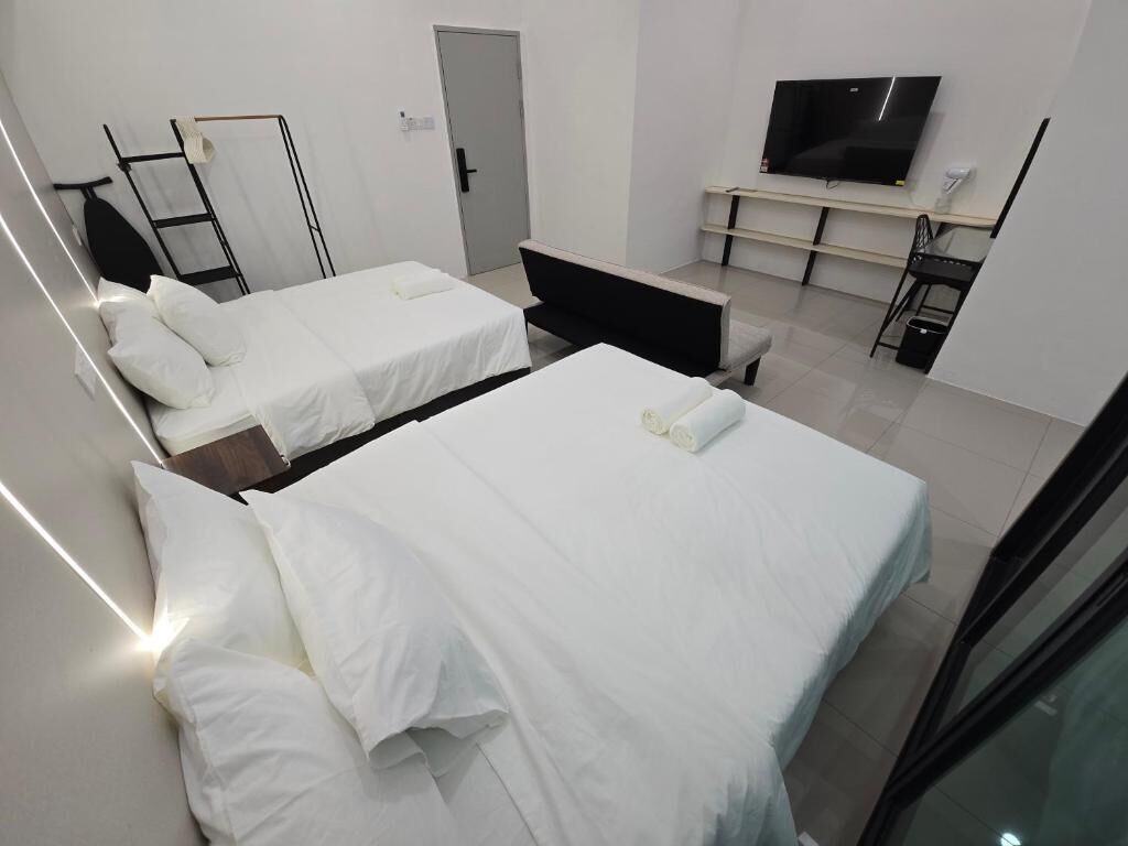 A hotel room with two beds, a TV, a desk, and a door.