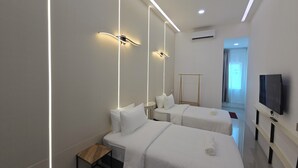 Una habitación de hotel moderna con dos camas, una mesita de madera, un televisor y un espejo grande.