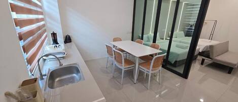 A modern kitchen with a sink, a coffee machine, and a dining area with a table and chairs.