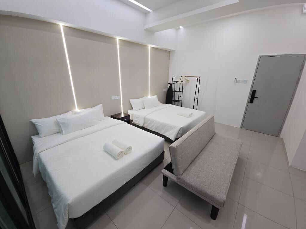 A modern hotel room with two beds, a seating area, and a wardrobe.
