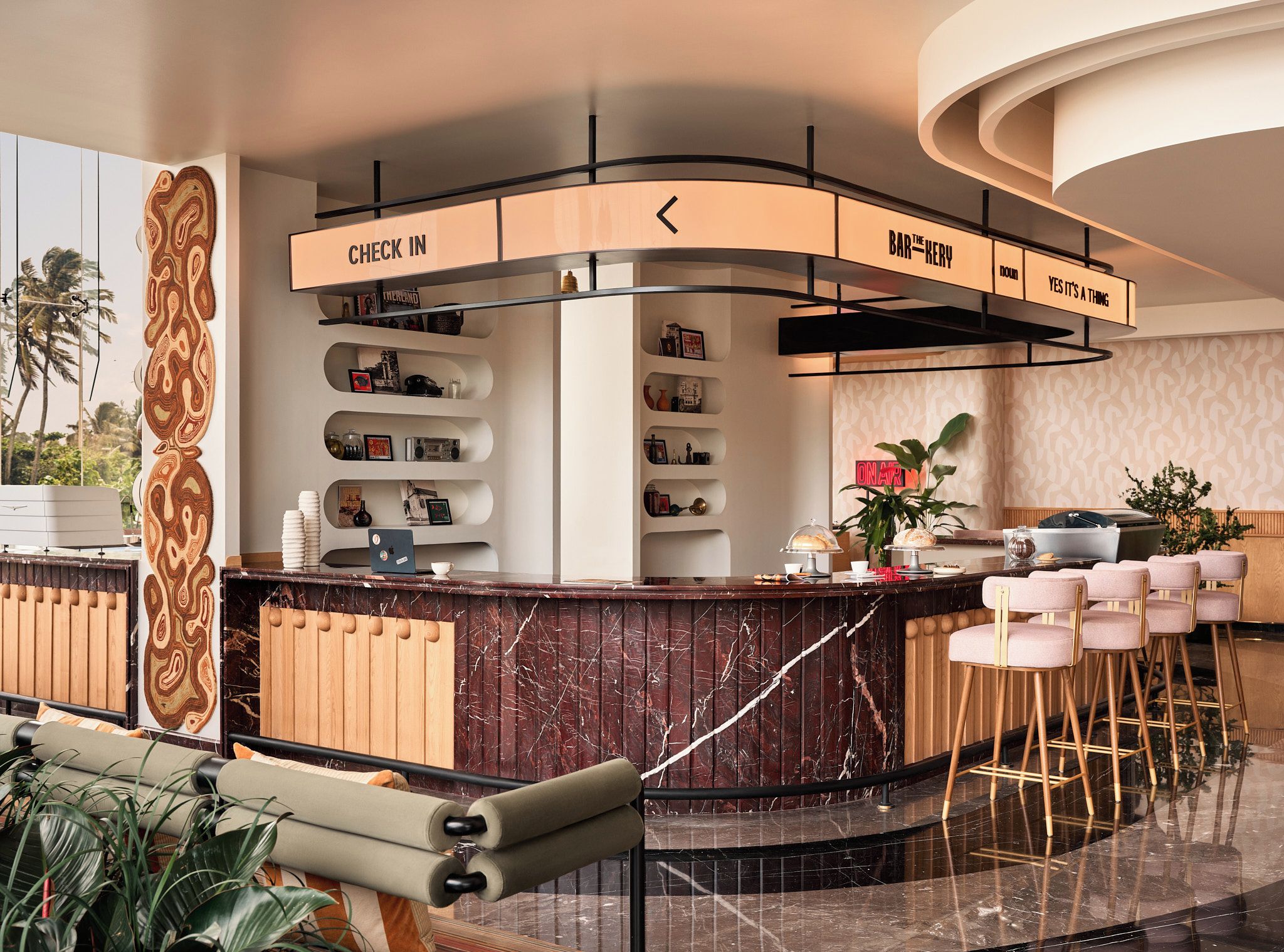 Eine moderne Bar mit einer gebogenen Theke, einem Check-in-Schild und Barhocker.
