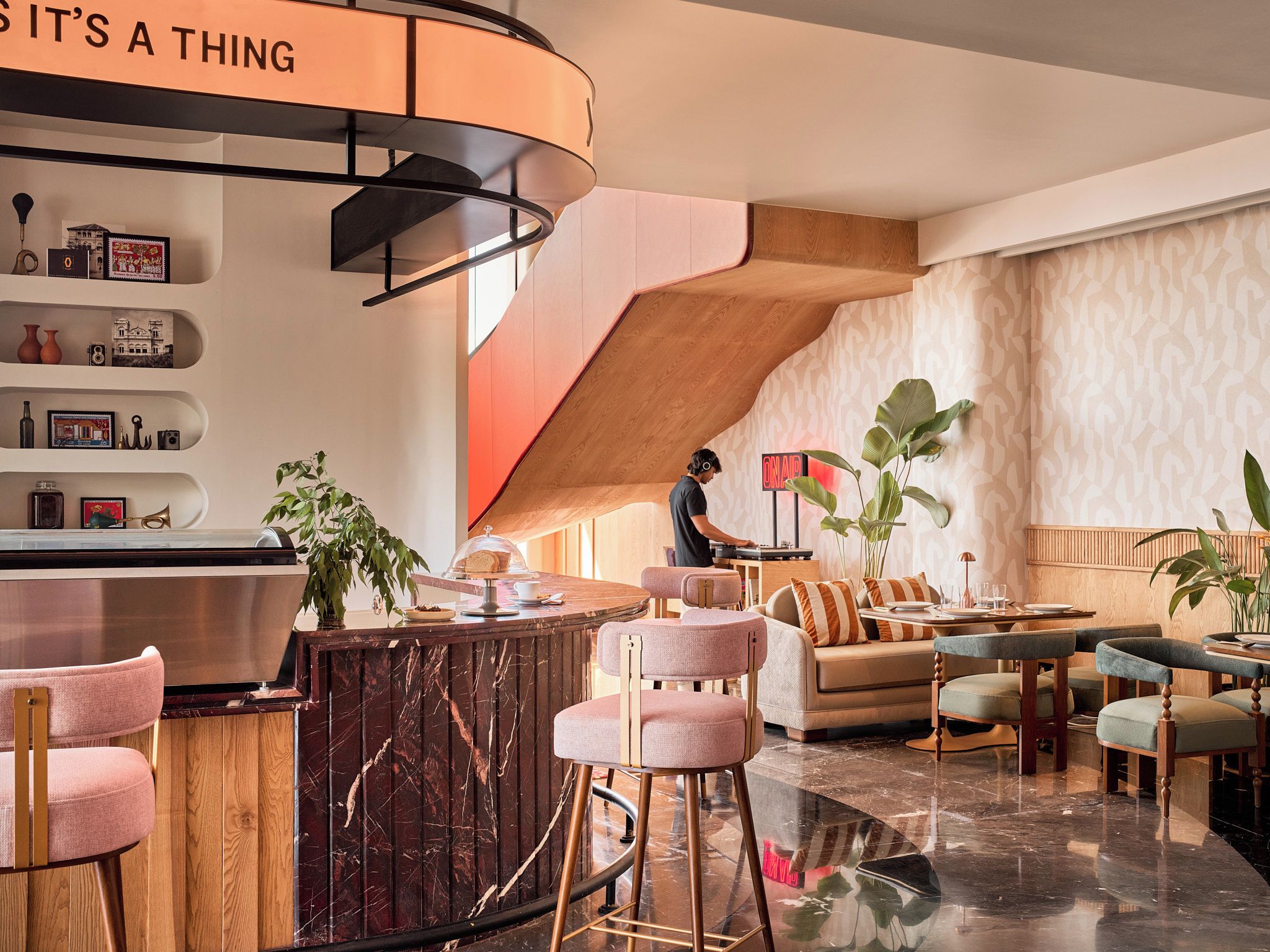 A modern interior with a curved bar, seating area, and a staircase.