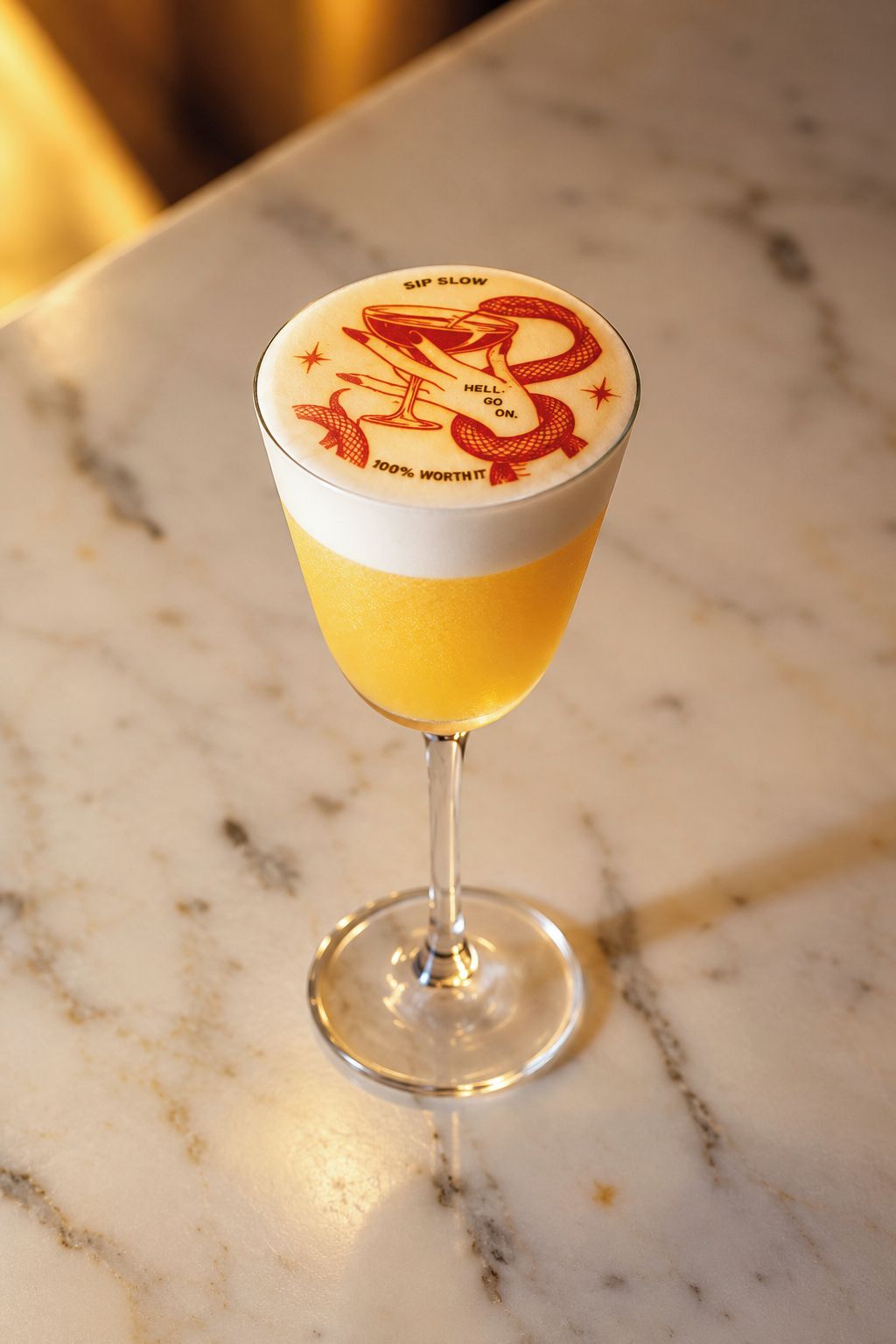 Ein Cocktailglas mit dekorativer Verzierung am Rand, auf einer Marmorplatte platziert.