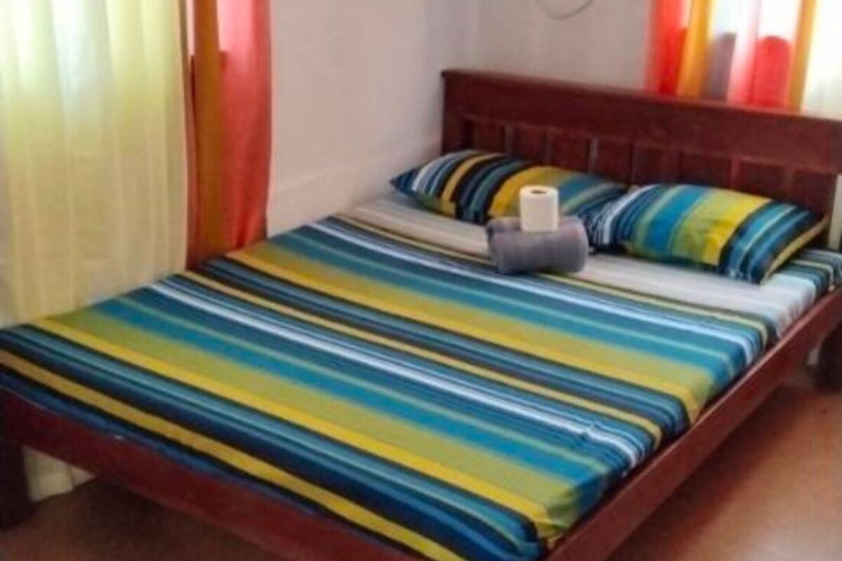 Un lit simple avec une couvre-lit à rayures, un oreiller et une serviette enroulée.