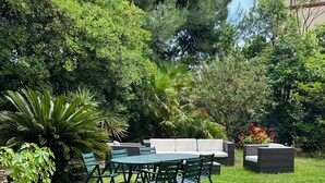 A garden patio with a table and chairs, surrounded by lush greenery and a variety of plants. - mare in pineta (San Benedetto del Tronto)
