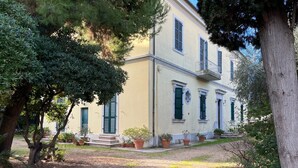 A two-story building with a symmetrical facade, green shutters, and a gravel driveway. - mare in pineta (San Benedetto del Tronto)