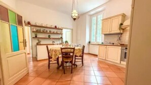 A spacious kitchen with a dining table, chairs, and a hanging light fixture. - mare in pineta (San Benedetto del Tronto)
