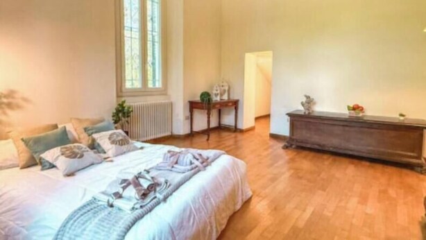 A bedroom with a large bed, a radiator, a window, and a wooden floor. - mare in pineta (San Benedetto del Tronto)