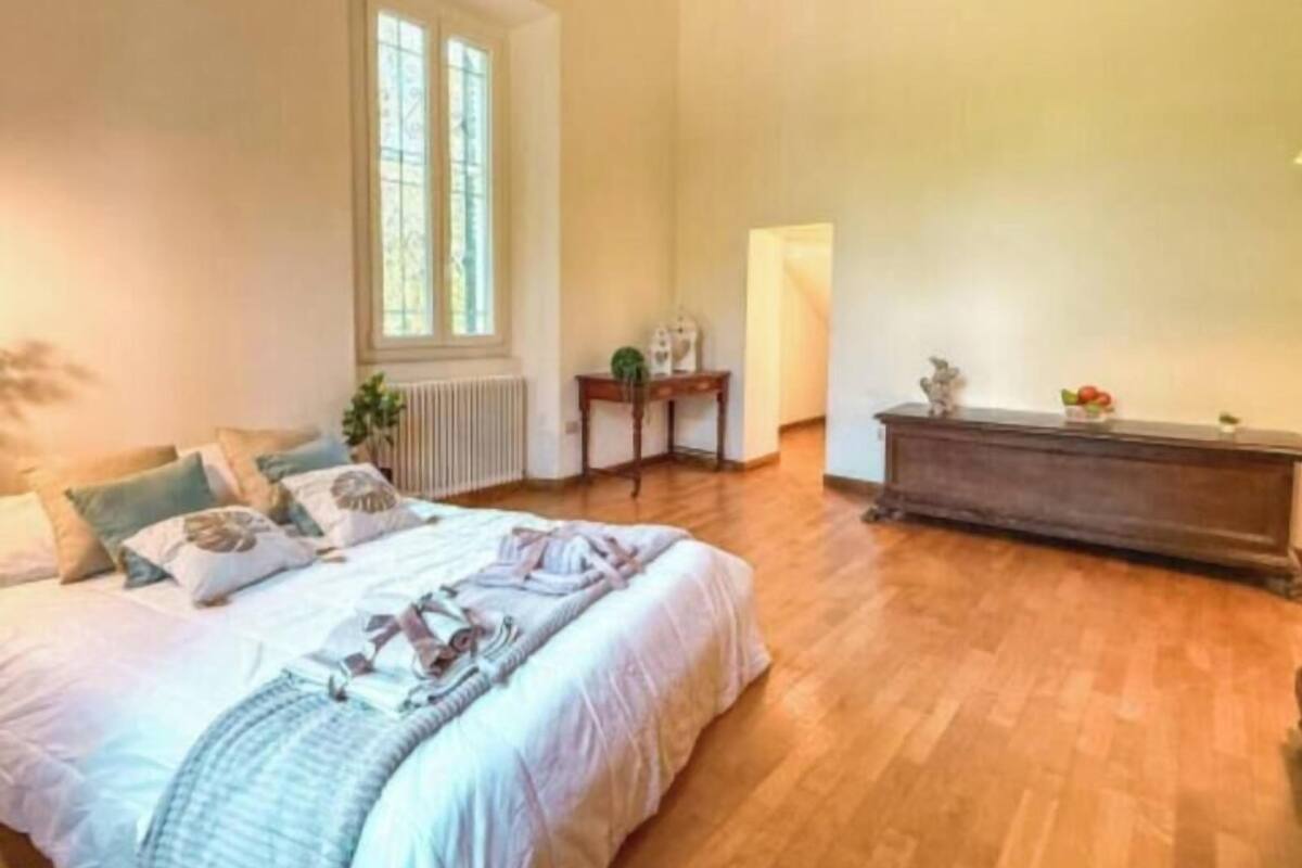 Un dormitorio con una cama grande, un radiador, una ventana y suelo de madera.