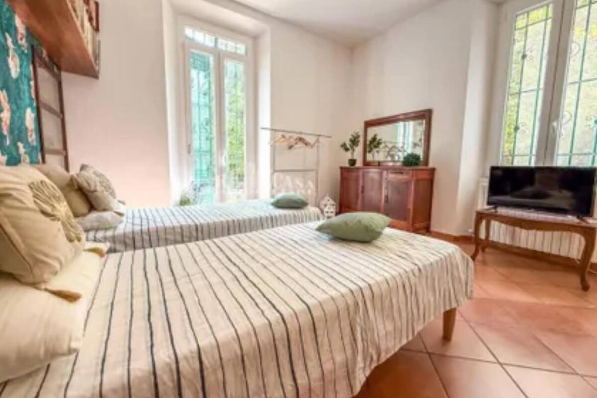 Una habitación con dos camas, televisión, armario y ventana.