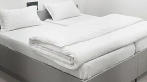 A modern, minimalist bedroom with a bed, pillows, and a nightstand. - Saran Homestay (Agra)