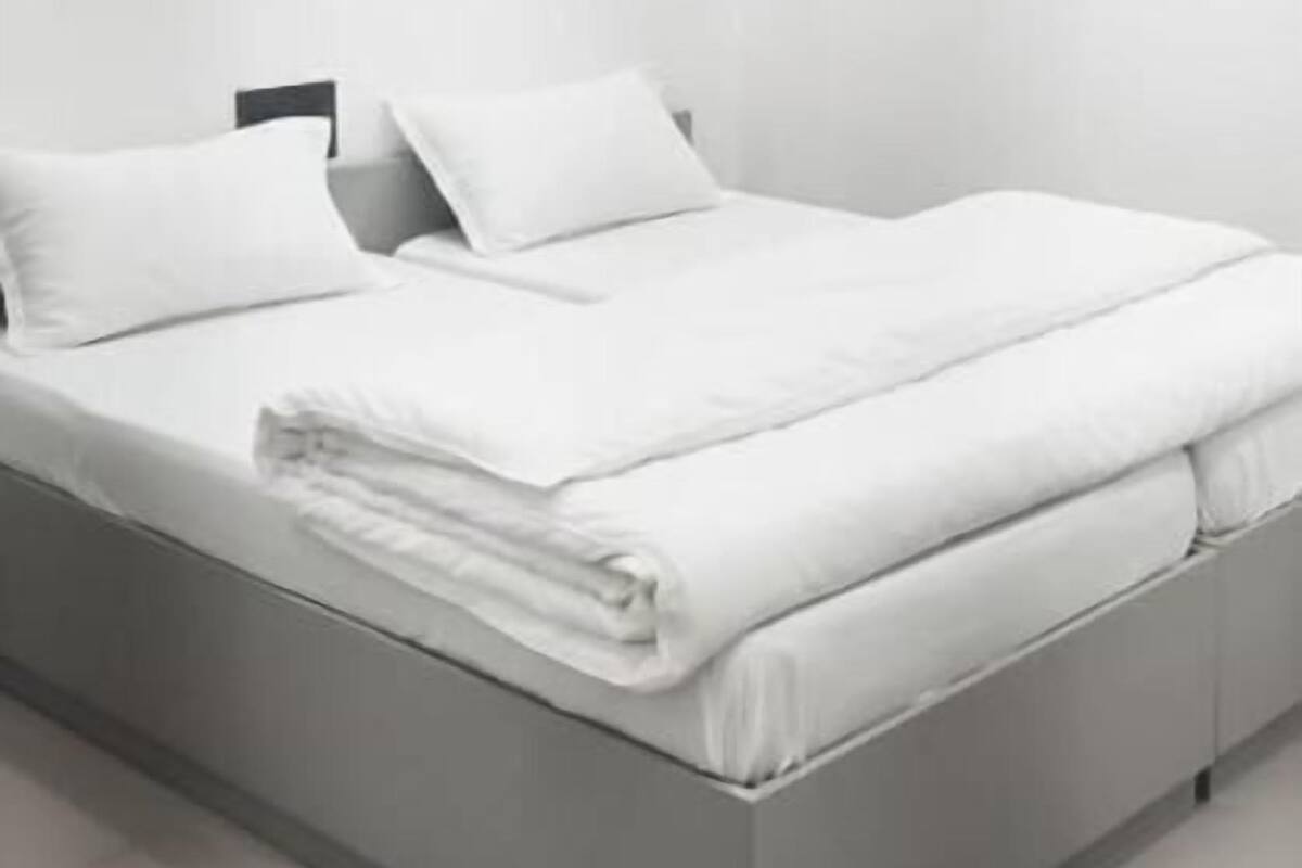 Un dormitorio moderno y minimalista con cama, almohadas y una mesita de noche.