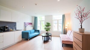 A modern living room with a sofa, a coffee table, and a dining area with a kitchen counter. - Cosy 1-bedroom Apartment, Antwerp (Antwerp)