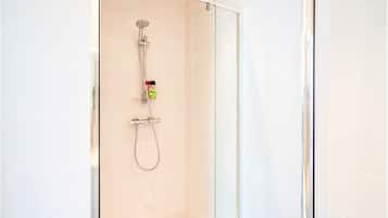Een douche met glazen wanden, een handdouche en een doucheslang.