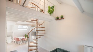 A modern interior with a spiral staircase, a dining area, and a green sofa. - Cosy 1-bedroom Apartment, Antwerp (Antwerp)