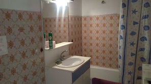 Ein Badezimmer mit Waschbecken, Spiegel und Duschvorhang.