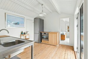 Moderni keittiö, jossa on ruostumattomasta teräksestä valmistettu allas, puukaapit ja sisäänrakennettu uuni.