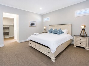 Une chambre à coucher avec un lit, des tables de chevet, une armoire et un tableau au mur.