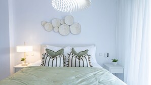 Ein modernes Schlafzimmer mit Bett, Nachttischen, einer Lampe und Wandbildern.