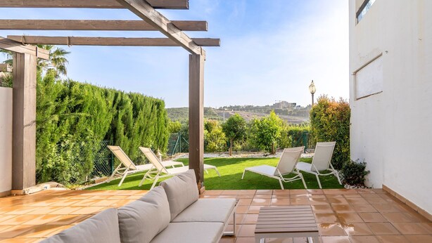 Eine Terrasse mit einer Couch, zwei Liegestühlen und einem Tisch.