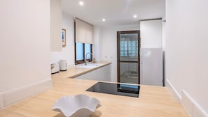 Eine moderne Küche mit einer Holzarbeitsplatte, einem Spülbecken und einer Glastür zum Balkon.