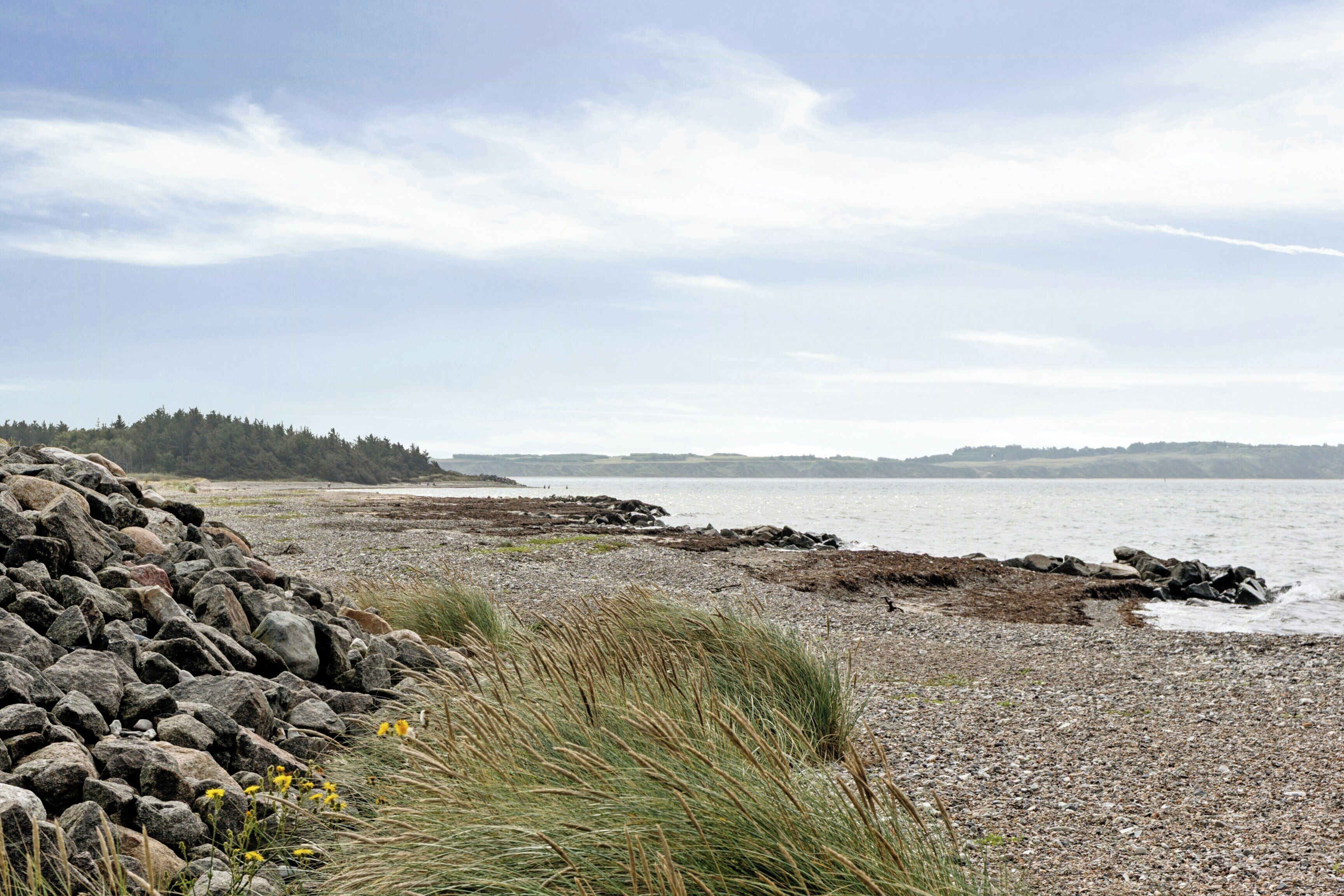 Un rivage rocheux offrant une vue sur l’eau et les collines lointaines.