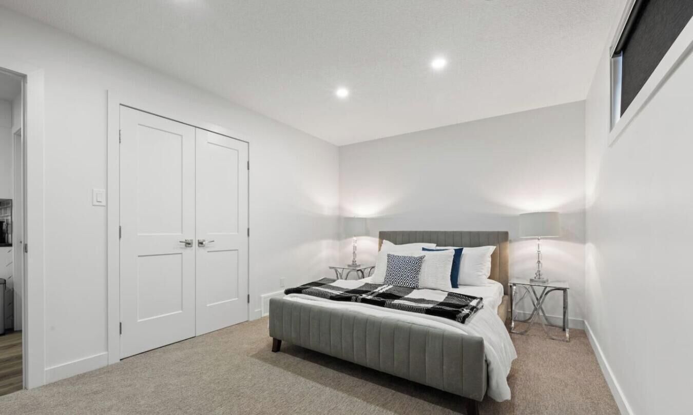 Quarto com cama, mesas de cabeceira, guarda-roupa e janela.
