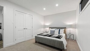 A bedroom with a bed, bedside tables, a wardrobe, and a window. - Orchards Delight | Near Airport | Sleeps 4 | WiFi (Edmonton)