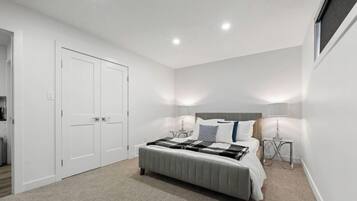 Quarto com cama, mesas de cabeceira, guarda-roupa e janela.