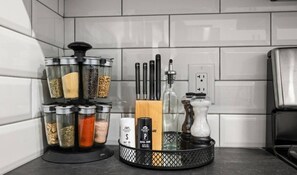 A kitchen with a spice rack, pepper grinder, salt shaker, and a knife block.