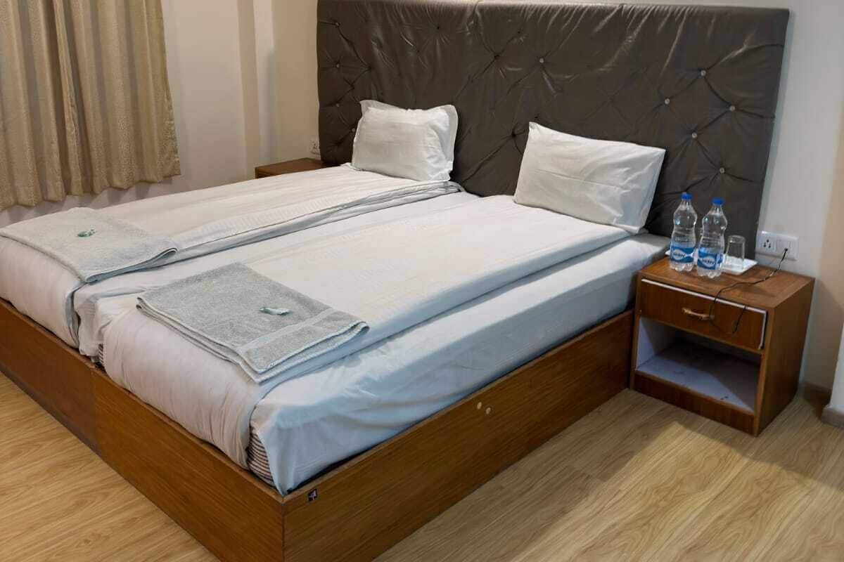 A double bed with a headboard, a nightstand with bottles, and a bedside table.