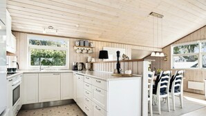 A modern kitchen with white cabinetry, a central island, and a dining area with striped chairs.