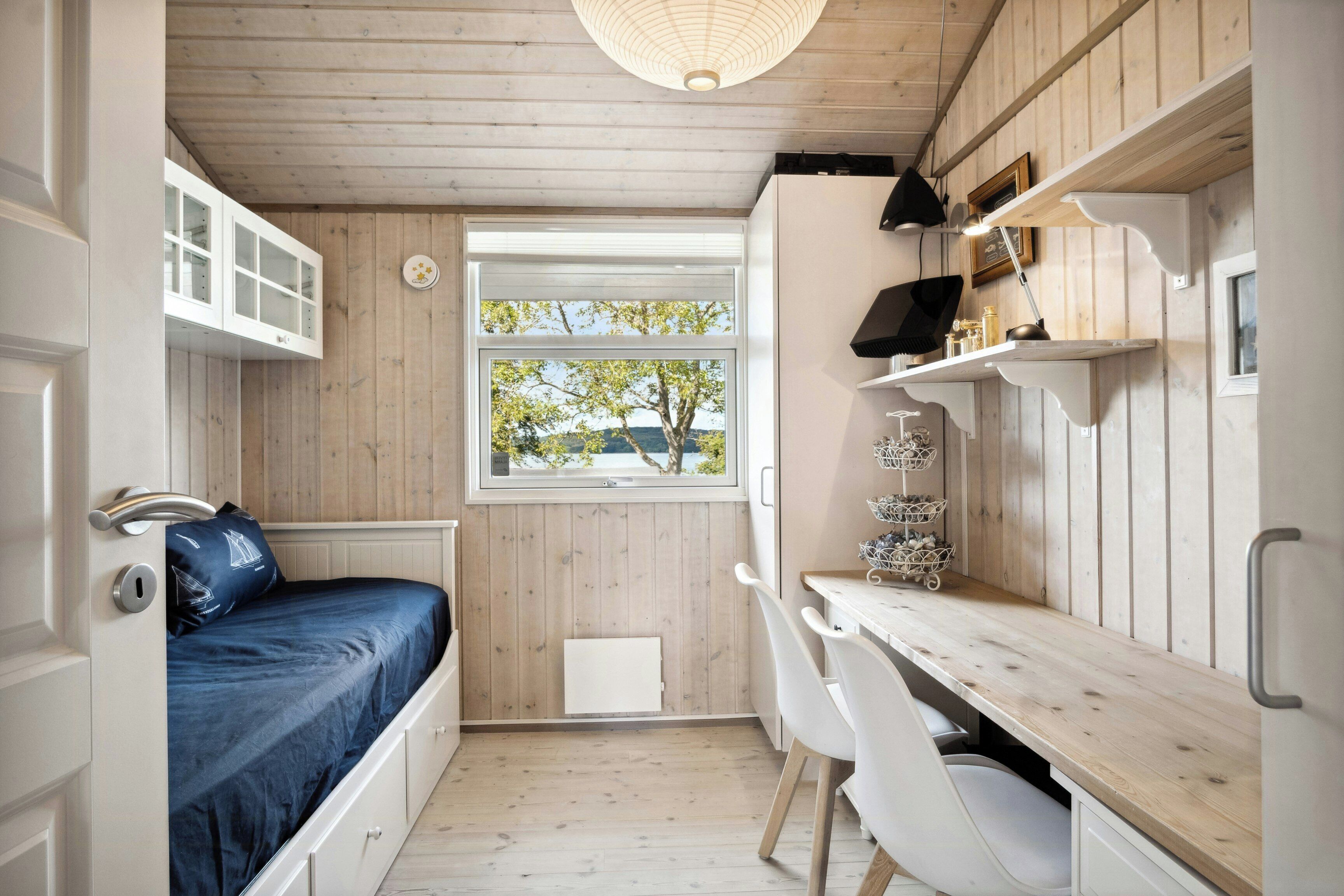 A compact room with a bed, a desk, and a window with a view.