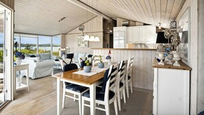 A modern kitchen with white cabinets, a wooden dining table, and a view of the outdoors.