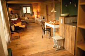 A cozy cabin interior with a wooden floor, a sofa, a dining table, and a chair. - Designer apartment in historic Allgäu farmhouse (Altusried)