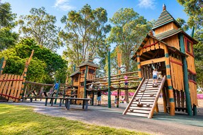 Une aire de jeux avec des structures en bois et un toboggan.